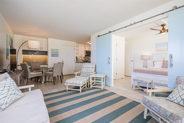 living room featuring ceiling fan, light tile patterned floors, and a barn door