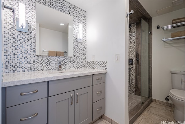 bathroom with tile patterned floors, decorative backsplash, toilet, vanity, and walk in shower