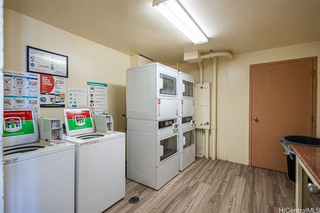 laundry area featuring stacked washer / drying machine, light hardwood / wood-style flooring, and washer and dryer