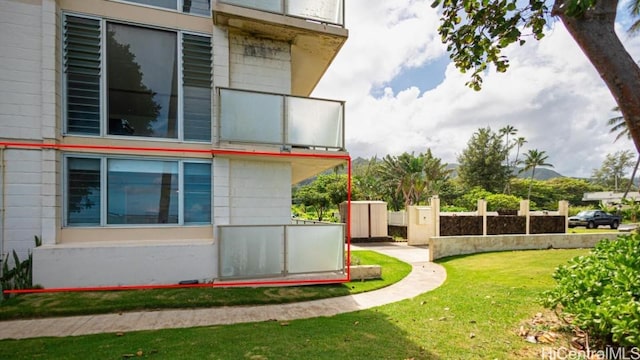 view of side of property with a lawn and a balcony