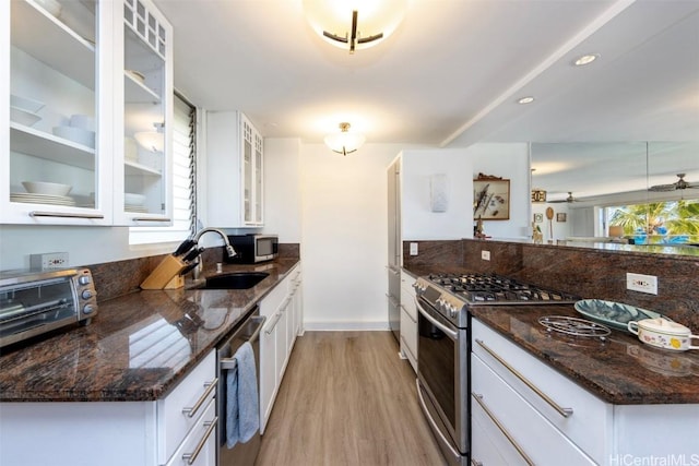 kitchen featuring white cabinets, stainless steel appliances, light hardwood / wood-style flooring, and dark stone countertops