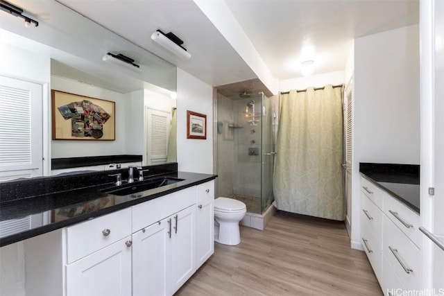 bathroom featuring hardwood / wood-style floors, vanity, toilet, and walk in shower