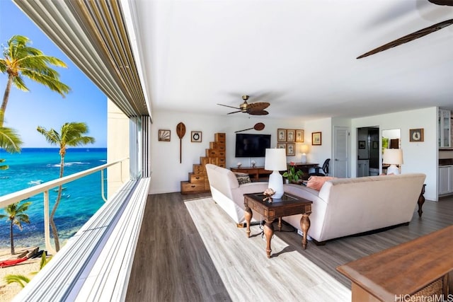 living room with hardwood / wood-style flooring, ceiling fan, and a water view