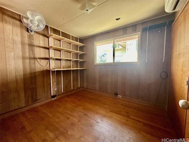 unfurnished room featuring hardwood / wood-style flooring, a wall mounted AC, and wood walls