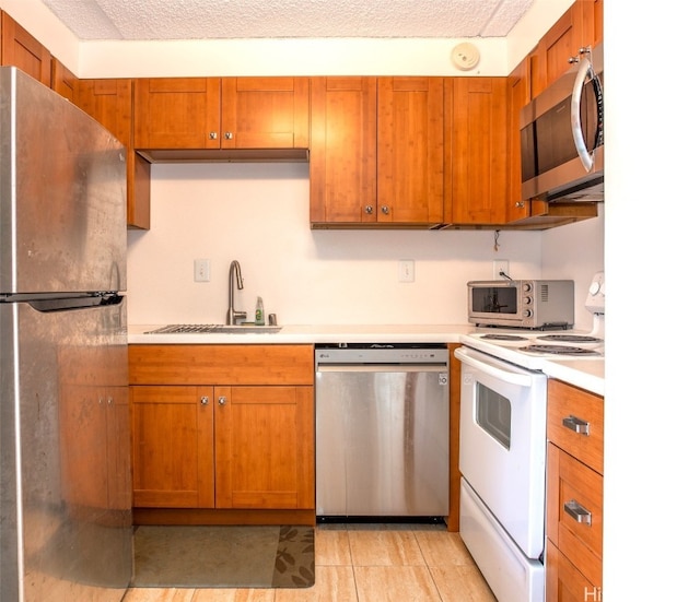 kitchen featuring appliances with stainless steel finishes, a textured ceiling, sink, and light tile patterned floors