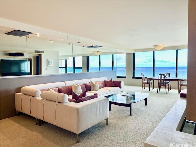 living room featuring a wealth of natural light, a water view, and carpet floors