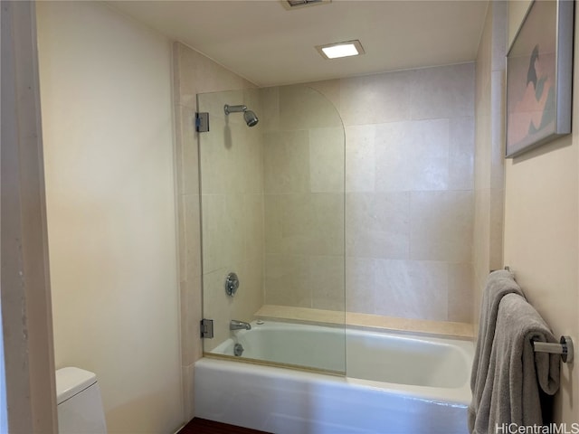 bathroom with toilet and tiled shower / bath combo