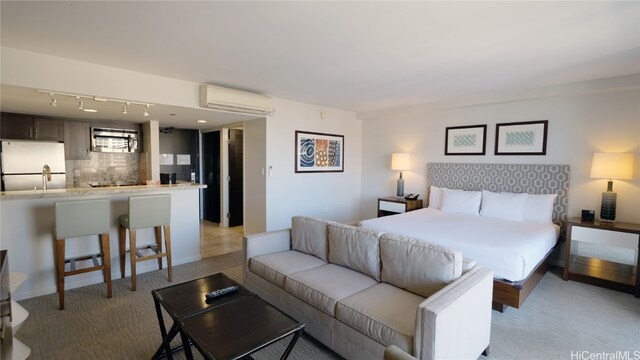 carpeted bedroom featuring an AC wall unit, track lighting, and white refrigerator