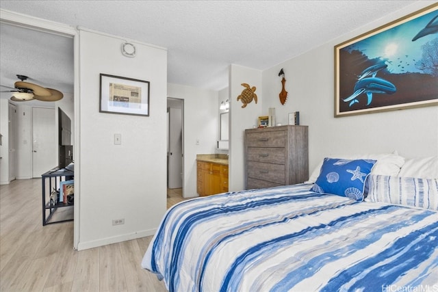 bedroom with a textured ceiling, ensuite bathroom, and light wood-type flooring