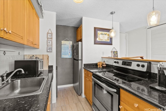 kitchen with a textured ceiling, light tile patterned flooring, stainless steel appliances, sink, and decorative light fixtures