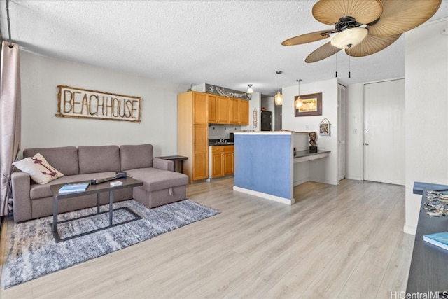 living room with light hardwood / wood-style floors, a textured ceiling, and ceiling fan