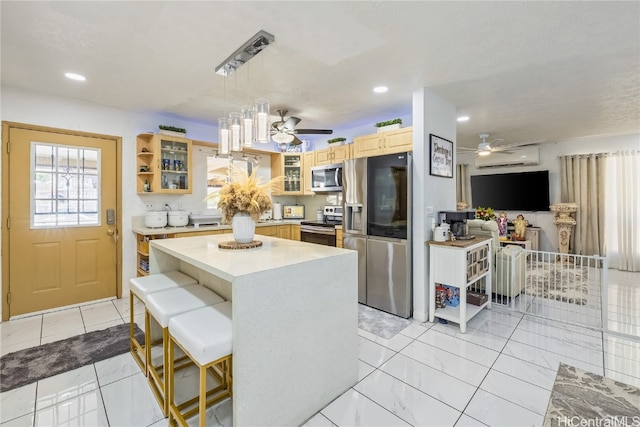 kitchen with hanging light fixtures, appliances with stainless steel finishes, a center island, and ceiling fan