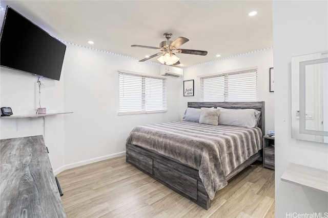 bedroom with ceiling fan, an AC wall unit, and light hardwood / wood-style floors