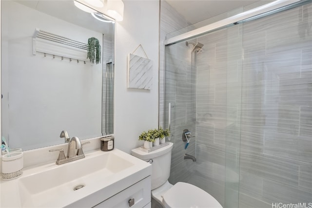 bathroom featuring vanity, a shower with door, and toilet