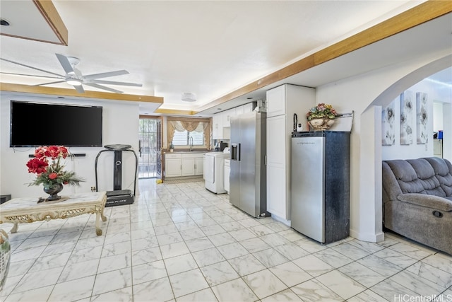 kitchen with stainless steel fridge with ice dispenser, stainless steel fridge, ceiling fan, washer / clothes dryer, and white cabinets