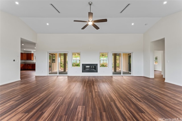 unfurnished living room featuring dark wood-type flooring, a healthy amount of sunlight, and high vaulted ceiling