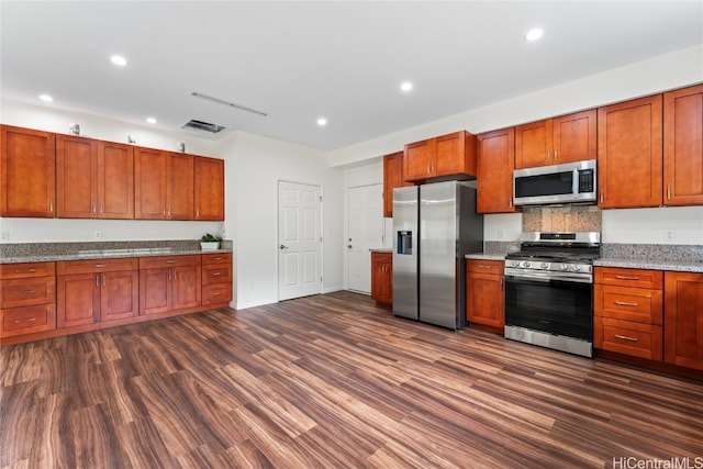 kitchen featuring appliances with stainless steel finishes, dark hardwood / wood-style floors, and light stone countertops