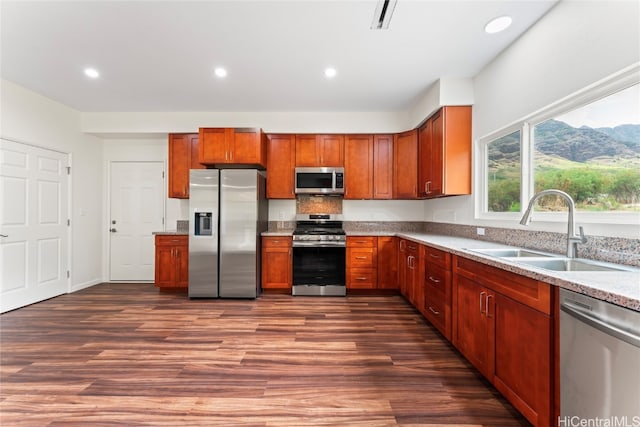 kitchen featuring dark wood-type flooring, appliances with stainless steel finishes, light stone countertops, and sink