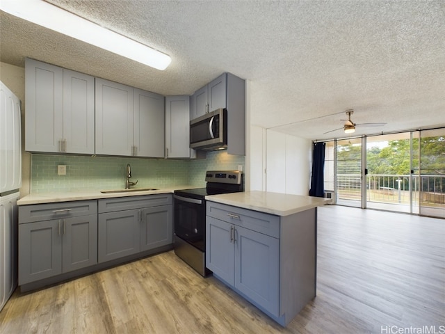 kitchen featuring tasteful backsplash, sink, light wood-type flooring, stainless steel appliances, and gray cabinets