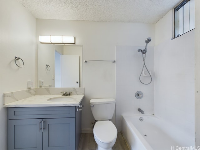 full bathroom with vanity, toilet, a textured ceiling, and tiled shower / bath