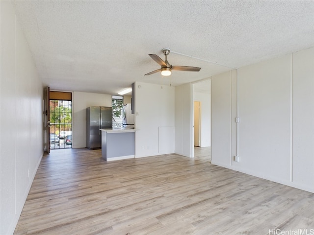 unfurnished living room featuring light hardwood / wood-style flooring, a textured ceiling, and ceiling fan