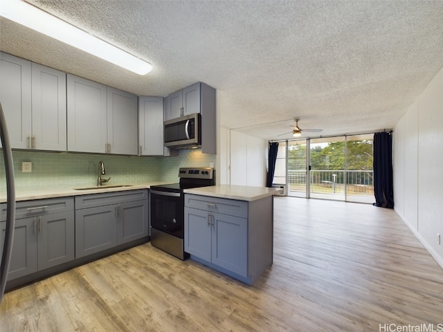 kitchen featuring backsplash, a textured ceiling, light hardwood / wood-style flooring, sink, and stainless steel appliances