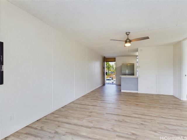 empty room featuring a textured ceiling, light hardwood / wood-style floors, and ceiling fan