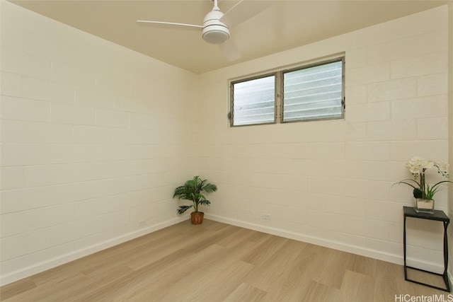 unfurnished room with ceiling fan, brick wall, and light wood-type flooring