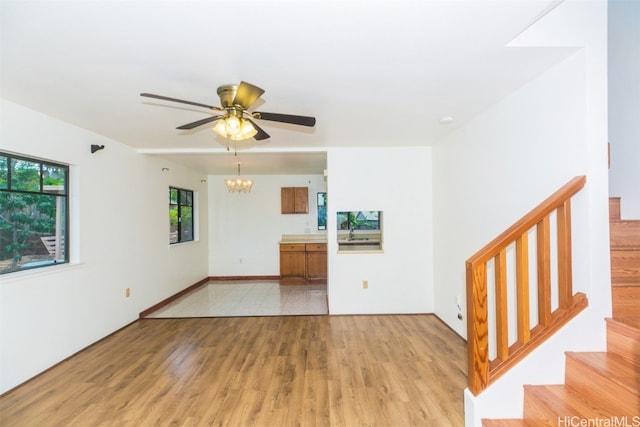 unfurnished living room with light hardwood / wood-style flooring, sink, and ceiling fan with notable chandelier