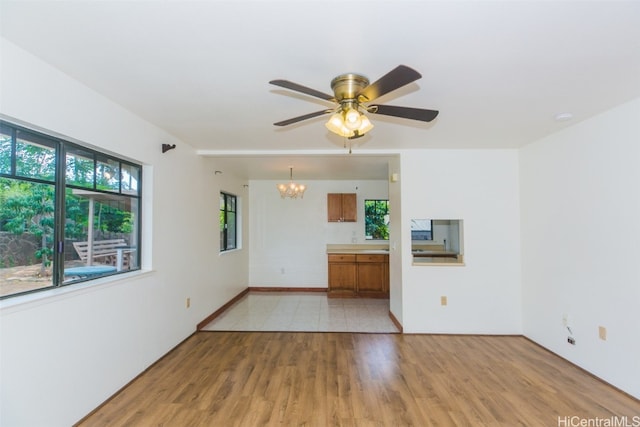 unfurnished room featuring ceiling fan with notable chandelier and light hardwood / wood-style floors