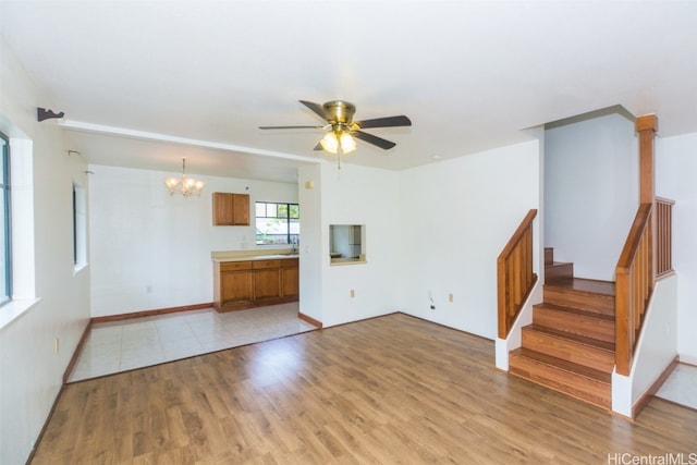 unfurnished living room featuring light hardwood / wood-style floors, sink, and ceiling fan with notable chandelier