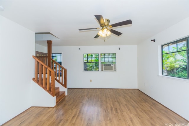 empty room with cooling unit, ceiling fan, light wood-type flooring, and a wealth of natural light