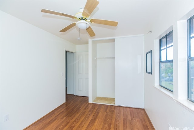 unfurnished bedroom featuring a closet, multiple windows, ceiling fan, and dark hardwood / wood-style flooring