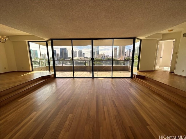 unfurnished room with hardwood / wood-style flooring, a notable chandelier, floor to ceiling windows, and a wealth of natural light