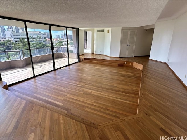 empty room featuring floor to ceiling windows, a textured ceiling, and hardwood / wood-style flooring