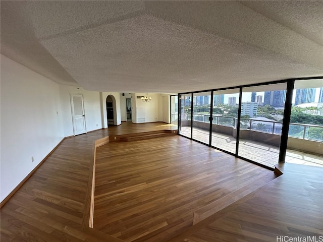 empty room with hardwood / wood-style floors, floor to ceiling windows, and a textured ceiling