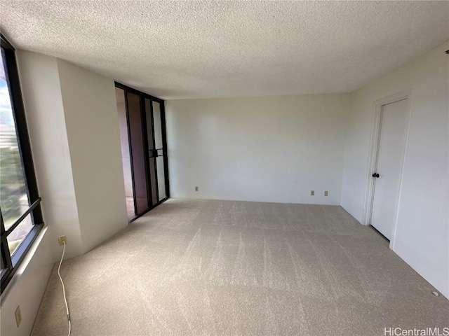 carpeted empty room featuring a textured ceiling