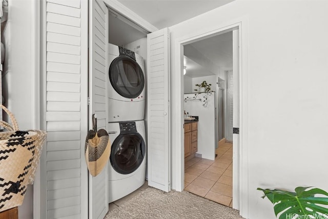 laundry room featuring stacked washer / dryer and light tile patterned floors