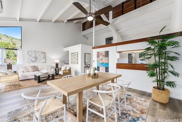 dining space with beamed ceiling, hardwood / wood-style flooring, high vaulted ceiling, and ceiling fan