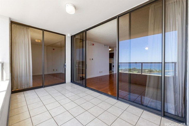 tiled spare room featuring a wall of windows