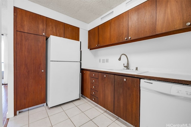 kitchen with a textured ceiling, sink, light tile patterned floors, and white appliances