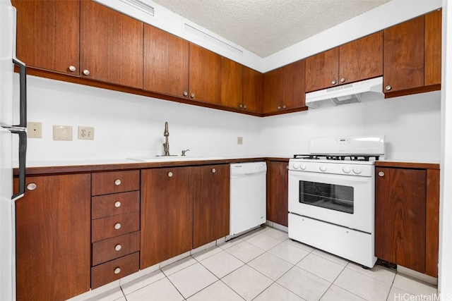 kitchen featuring white appliances, light tile patterned flooring, a textured ceiling, and sink