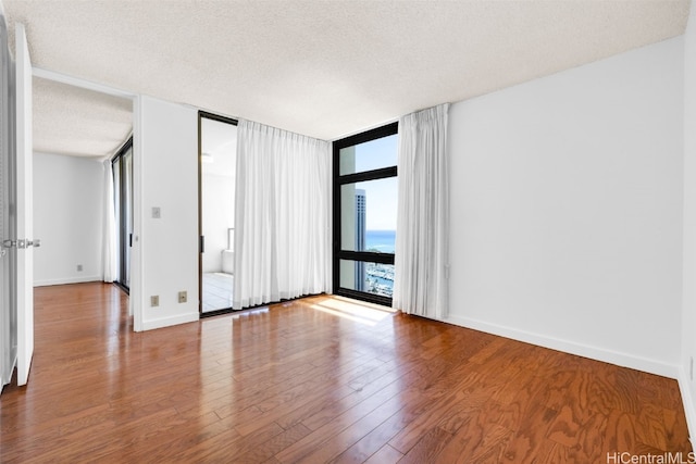 unfurnished room with a textured ceiling, hardwood / wood-style flooring, and floor to ceiling windows