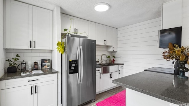 kitchen with sink, white cabinets, a textured ceiling, tasteful backsplash, and stainless steel fridge with ice dispenser