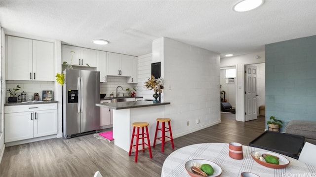 kitchen with white cabinets, stainless steel fridge, and a kitchen breakfast bar