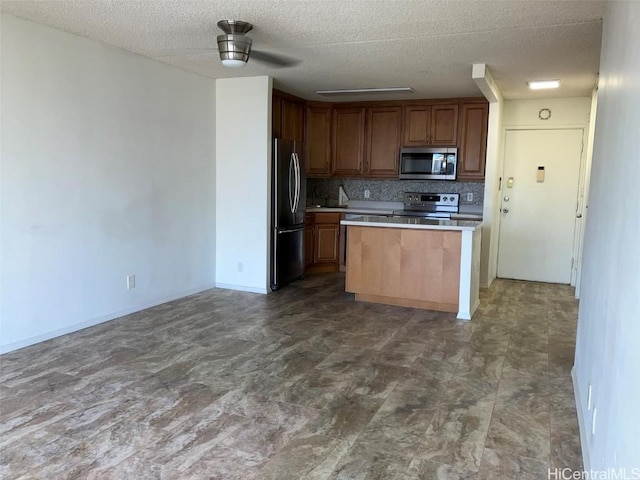 kitchen with a textured ceiling, appliances with stainless steel finishes, and tasteful backsplash