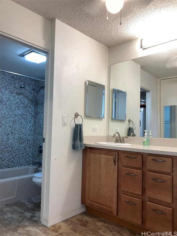 full bathroom with vanity, toilet, tiled shower / bath combo, and a textured ceiling