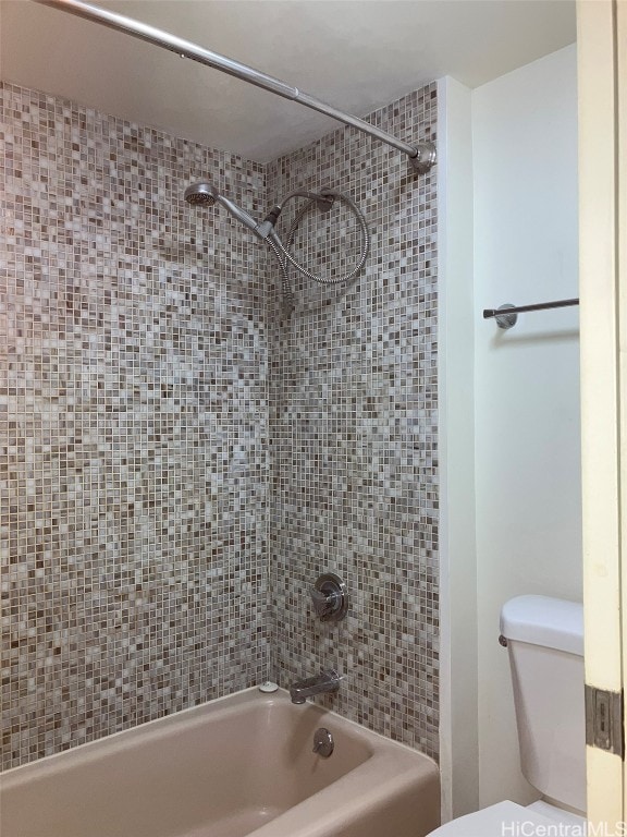 bathroom featuring toilet and tiled shower / bath