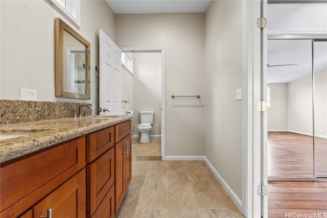 full bathroom with double vanity, toilet, baseboards, and a sink