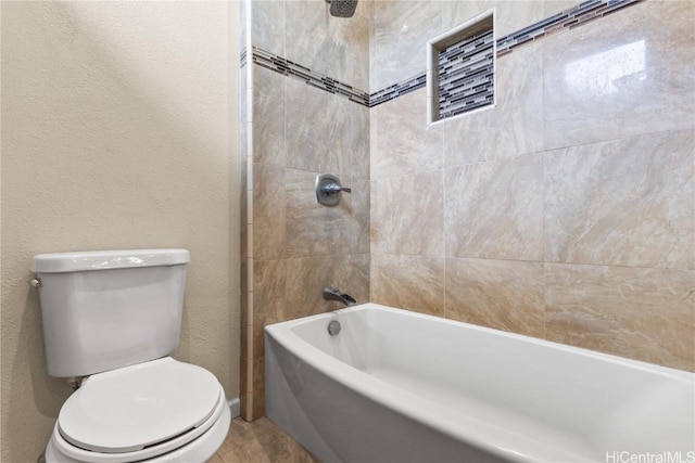 full bathroom with tub / shower combination, toilet, and a textured wall